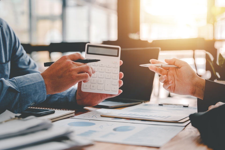 Personas revisan gráficas mientras hacen cálculos en una calculadora